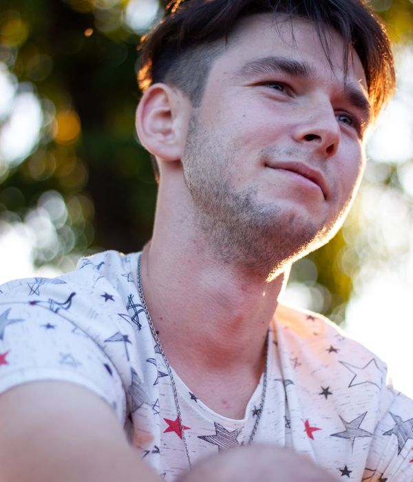 A person with a serene expression, radiating positive energy outdoors.